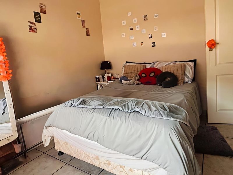 A standard bedroom featuring tiled flooring and a neutral wall finish, providing a functional space for rest.