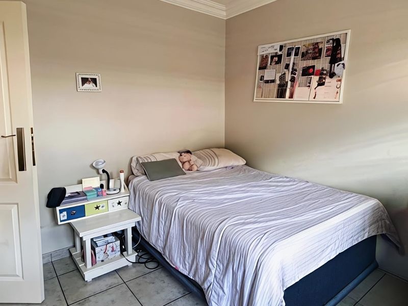 A functional bedroom featuring tiled flooring and classic ceiling cornicing, providing a neutral base for personalization.