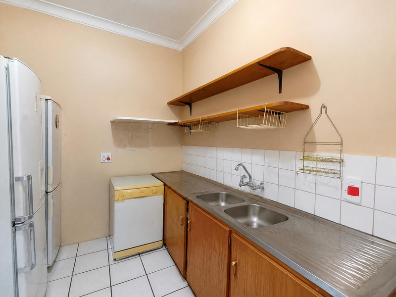 Functional scullery area featuring wooden cabinetry, double stainless steel sink, tiled splashback, and open shelving for additional storage.