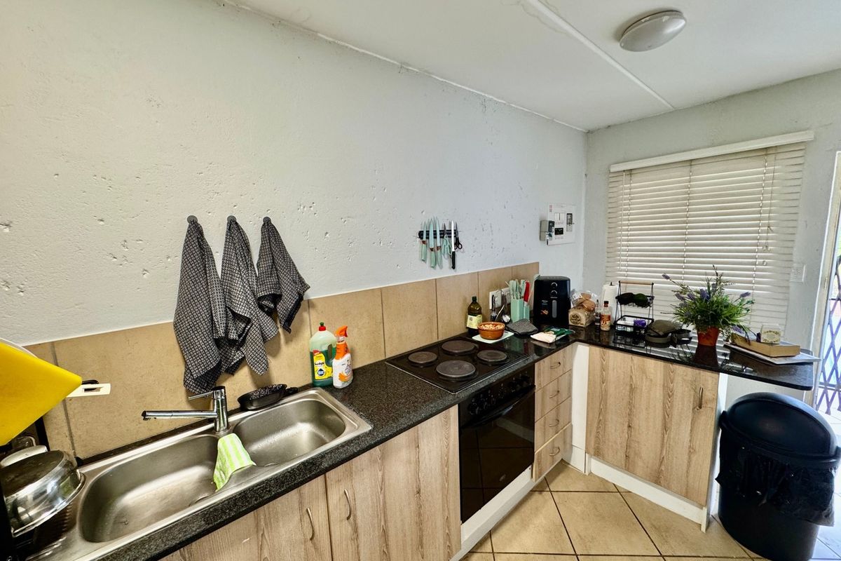 Compact kitchen featuring laminate cabinetry, granite countertops, built-in oven and hob, and tiled backsplash, with visible ceiling maintenance required.