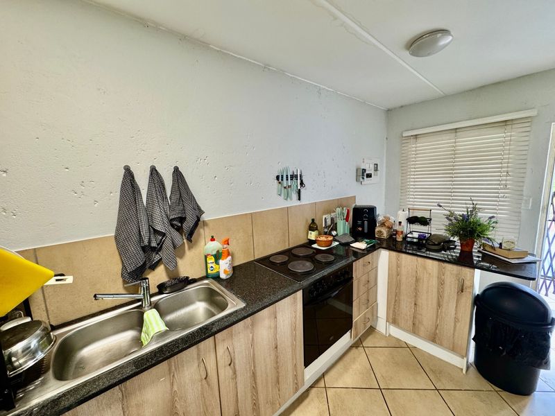 Compact kitchen featuring laminate cabinetry, granite countertops, built-in oven and hob, and tiled backsplash, with visible ceiling maintenance required.