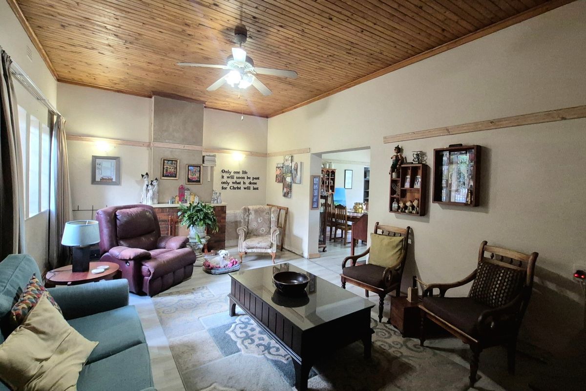 Spacious living room featuring a warm timber tongue and groove ceiling, ceiling fan, and a classic brick fireplace surround.
