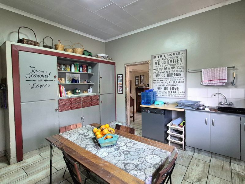 A functional kitchen featuring built-in cabinetry, a tiled backsplash, and tiled flooring, offering a practical layout with potential for modern cosmetic updates.