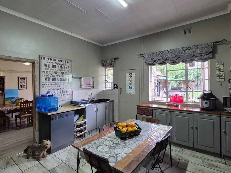 A functional kitchen featuring built-in cabinetry, tiled flooring, and a window with security bars, offering a practical space with potential for modern updates.