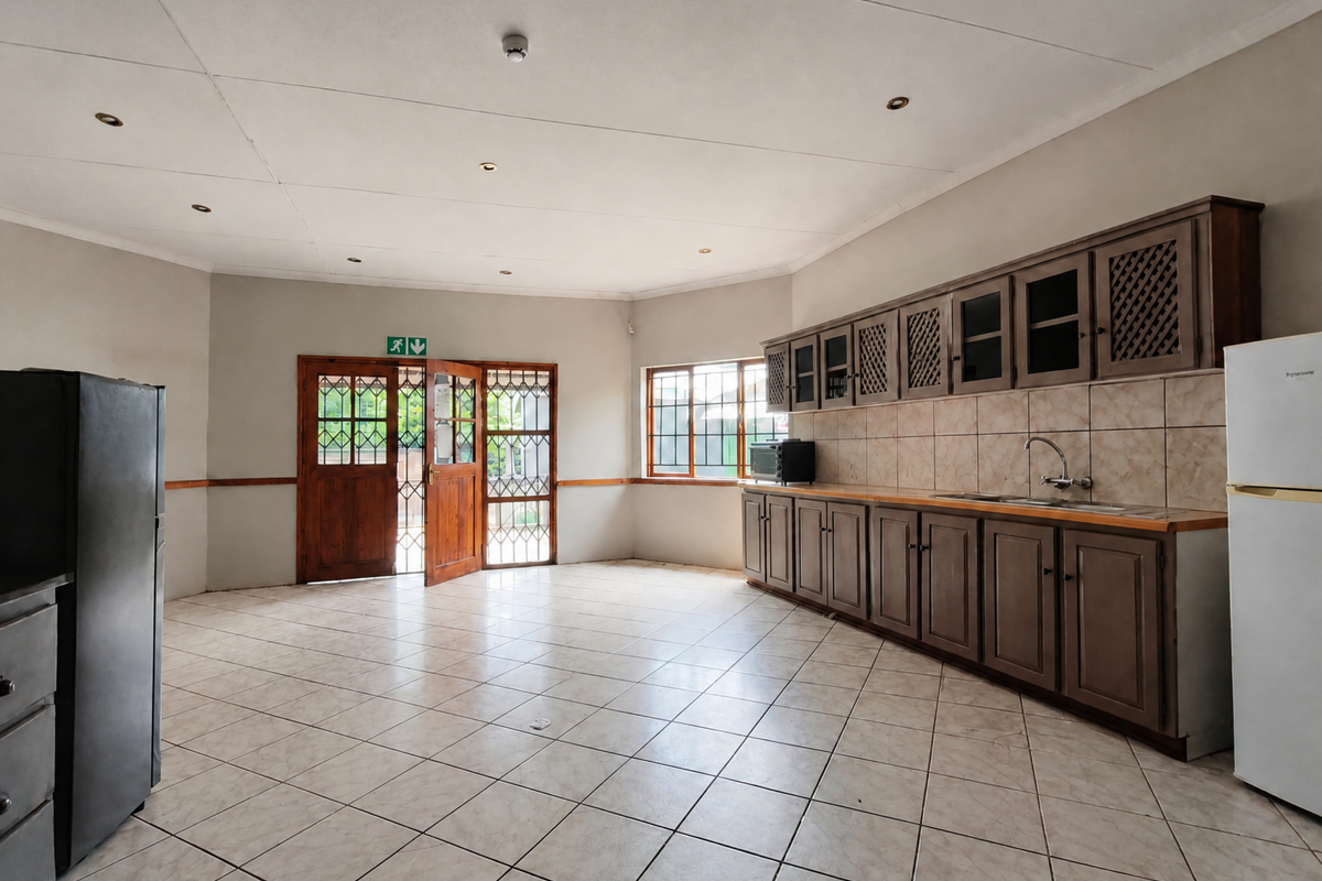 Spacious kitchen featuring built-in wooden cabinetry, tiled flooring, and a tiled backsplash, offering a functional layout with direct access to the exterior.