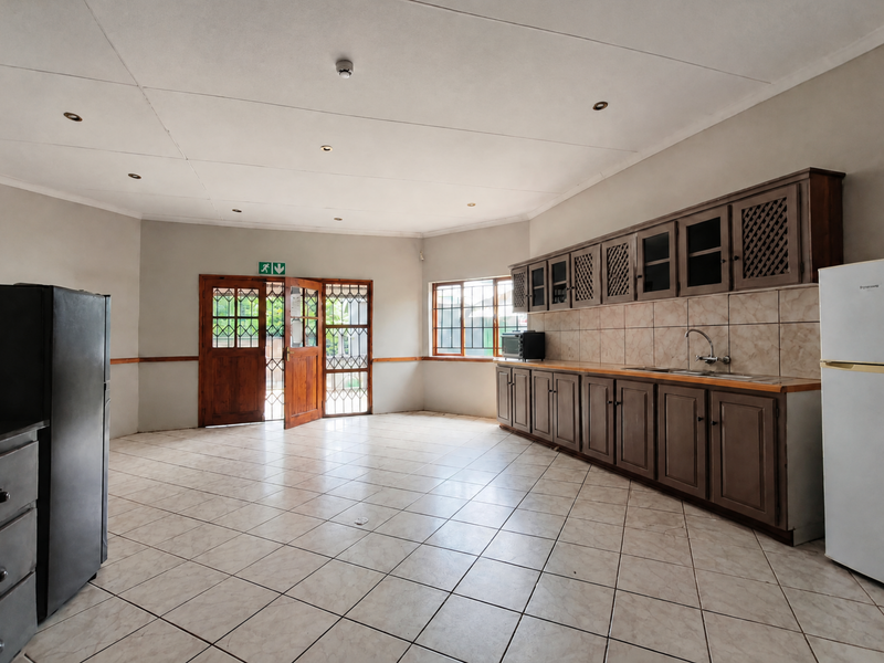 Spacious kitchen featuring built-in wooden cabinetry, tiled flooring, and a tiled backsplash, offering a functional layout with direct access to the exterior.