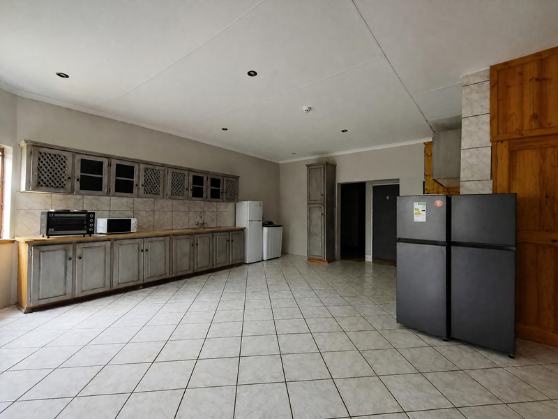 Spacious kitchen featuring extensive built-in cabinetry, tiled flooring, and a tiled backsplash, offering a functional layout with ample storage space.