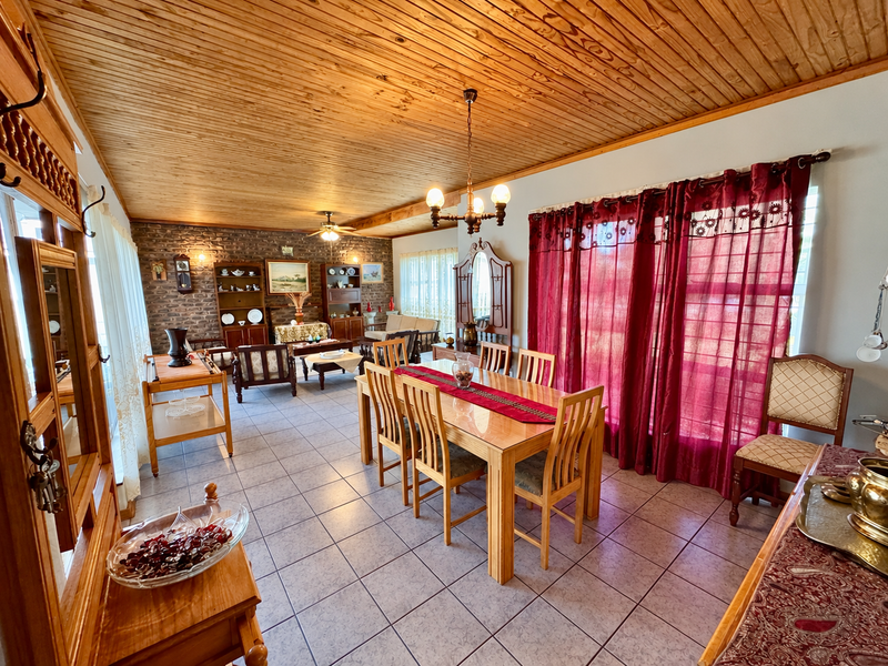 Spacious open-plan living and dining area featuring a warm timber ceiling, exposed brick wall, and large sliding doors providing ample natural light.