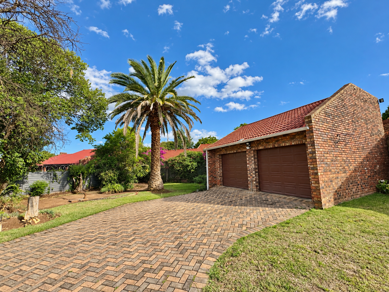 A well-maintained double garage featuring a classic brick facade, tiled roof, and a neat paved driveway set within a landscaped garden.