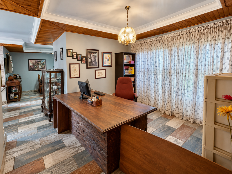 A home office featuring timber ceiling paneling, decorative cove molding, and multi-toned ceramic floor tiles, providing a functional workspace with natural light.