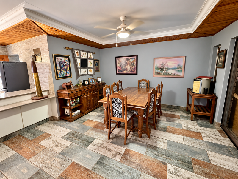 Spacious dining area featuring decorative tiled flooring, a timber-trimmed ceiling with a fan, and a stone-accented breakfast counter connecting to the kitchen.