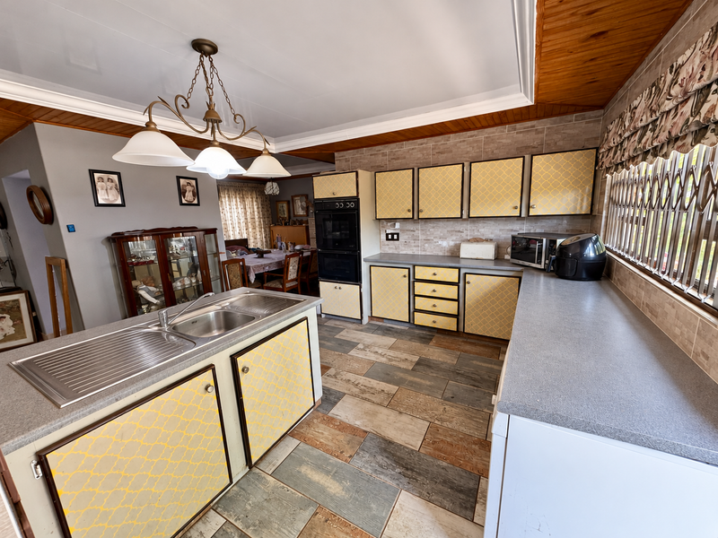 Spacious kitchen featuring built-in oven, double sink, and ample cabinetry, with a functional layout and tiled flooring throughout.
