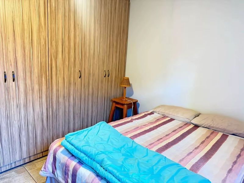 A bedroom featuring floor-to-ceiling built-in wooden cupboards and tiled flooring.