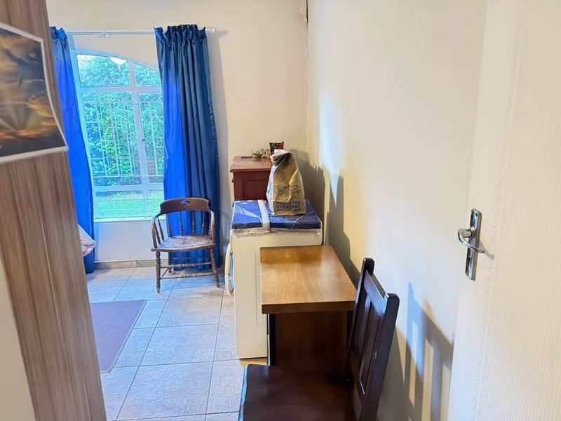 A functional living area featuring tiled flooring and an arched window with access to the exterior, offering a neutral base for potential updates.