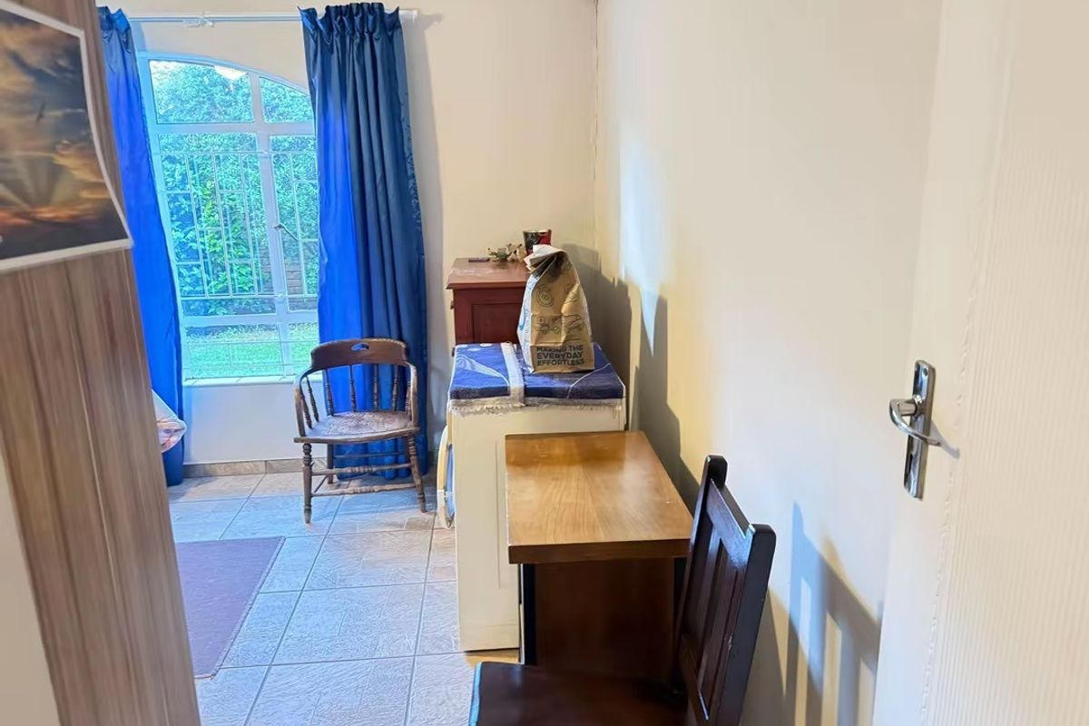 A functional living area featuring tiled flooring and an arched window with access to the exterior, offering a neutral base for potential updates.