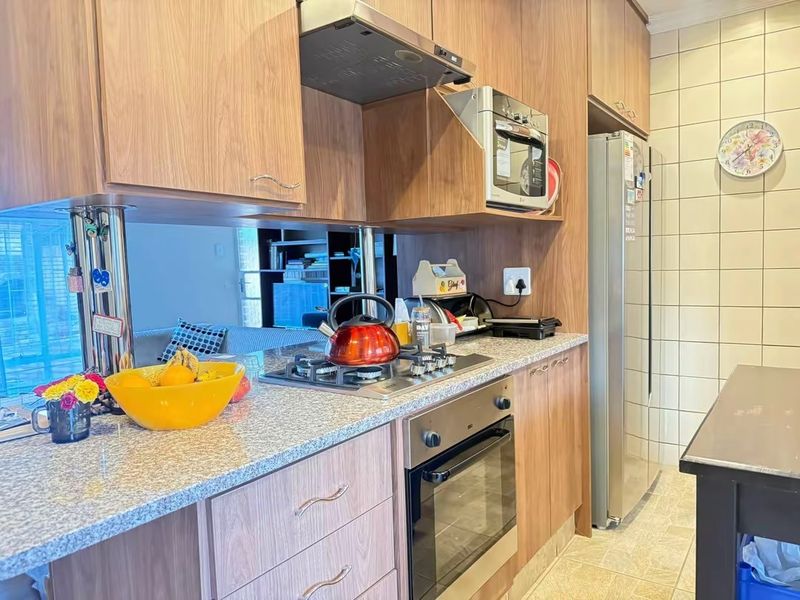 A functional kitchen featuring wood-finish cabinetry, granite countertops, a gas hob, built-in oven, and tiled backsplash.