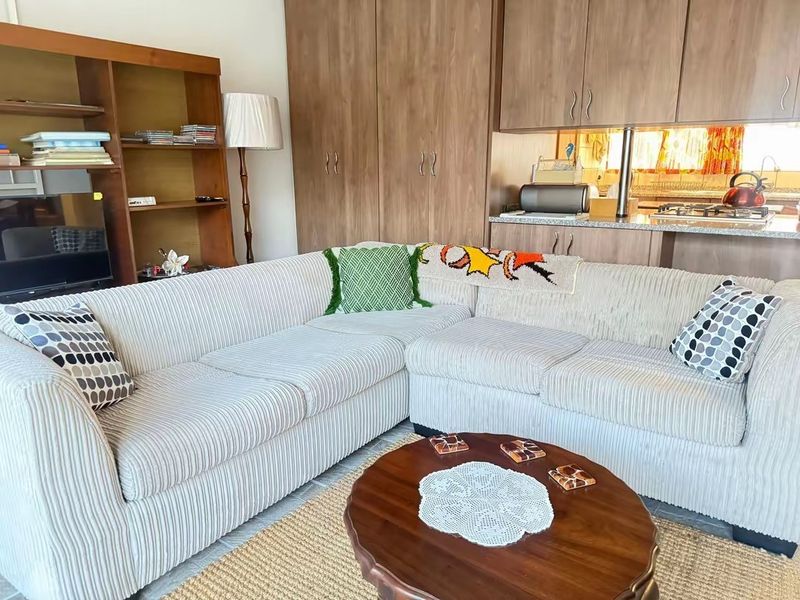 Open plan living area featuring built-in cabinetry and a functional kitchen corner with granite countertops and a gas hob.