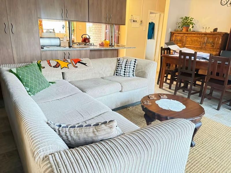 Open plan living and dining area featuring a breakfast bar and kitchen cabinetry, providing a functional and connected layout for daily living.