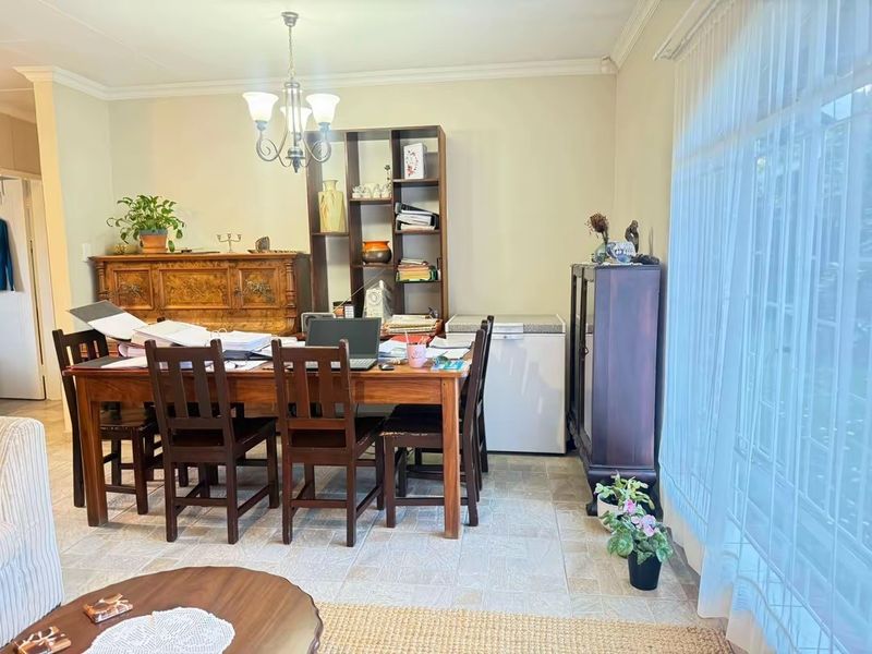 A functional dining room featuring tiled flooring, coved ceilings, and a large window that provides ample natural light.