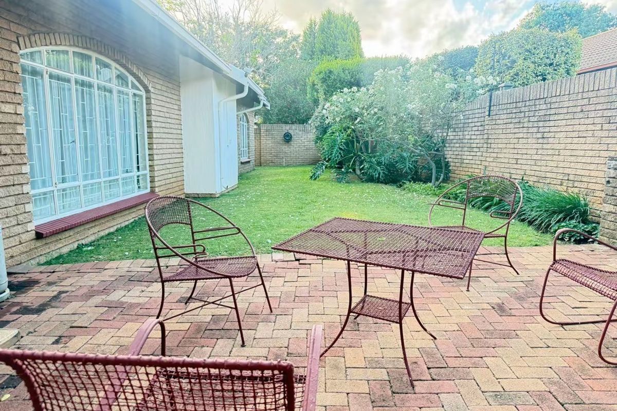 A private rear garden featuring a brick-paved patio area, established lawn, and secure brick boundary walls.