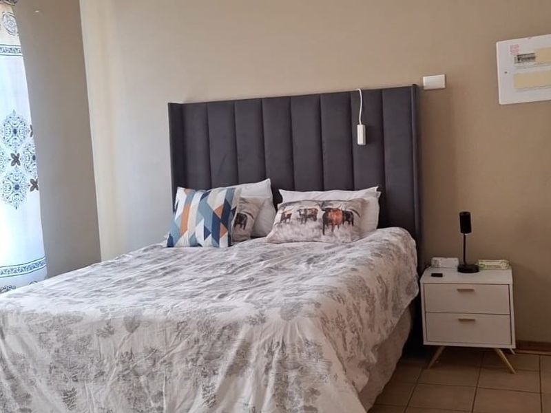 A bedroom featuring tiled flooring and a wall-mounted heater, providing a functional and comfortable living space.