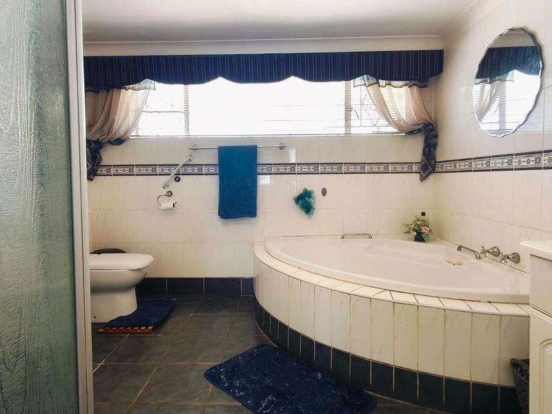 A functional bathroom featuring a corner bathtub, tiled wall finishes, and a vanity cabinet, offering a classic layout with essential fixtures.