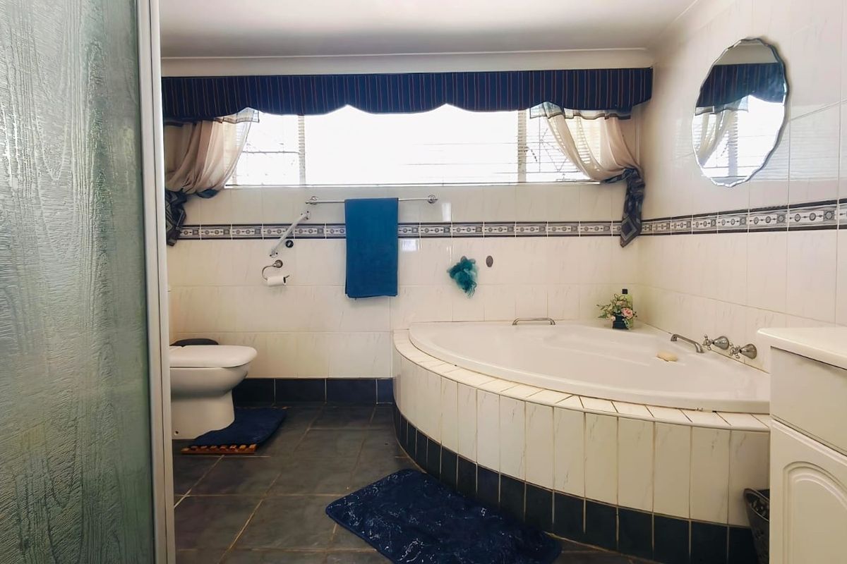 A functional bathroom featuring a corner bathtub, tiled wall finishes, and a vanity cabinet, offering a classic layout with essential fixtures.