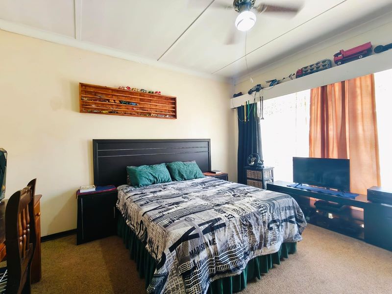 A functional bedroom featuring a ceiling fan and carpeted flooring, offering a comfortable space with neutral wall finishes.