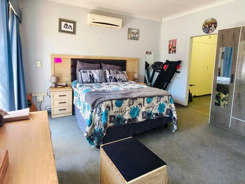 Spacious bedroom featuring carpet flooring, a built-in wardrobe, and a wall-mounted split-system air conditioner for climate control.