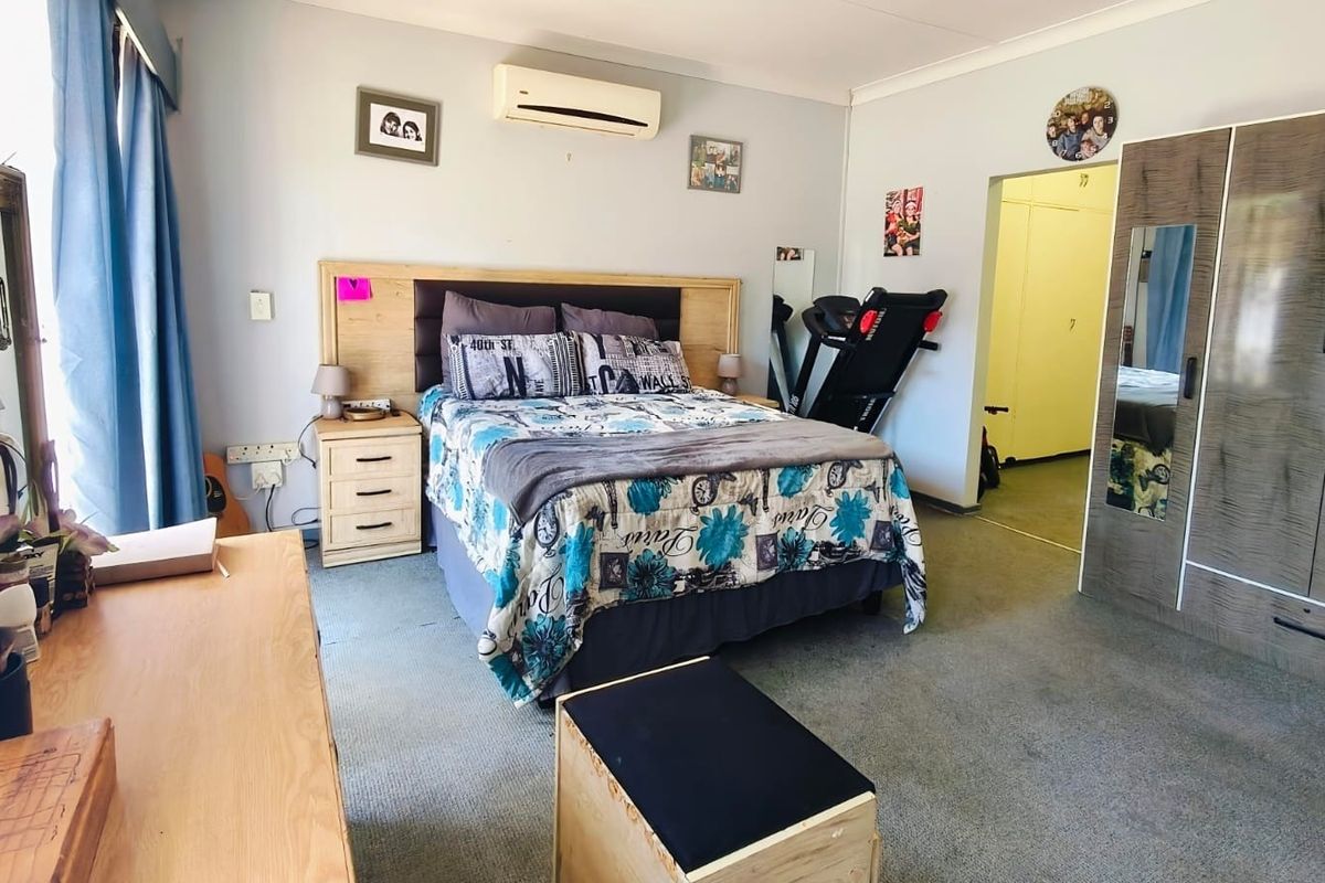 Spacious bedroom featuring carpet flooring, a built-in wardrobe, and a wall-mounted split-system air conditioner for climate control.