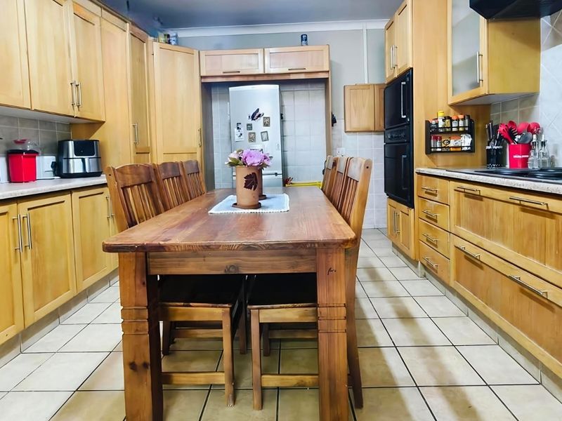 Spacious kitchen featuring extensive wooden cabinetry, built-in double oven, gas hob, and tiled flooring, offering a functional layout with ample storage space.