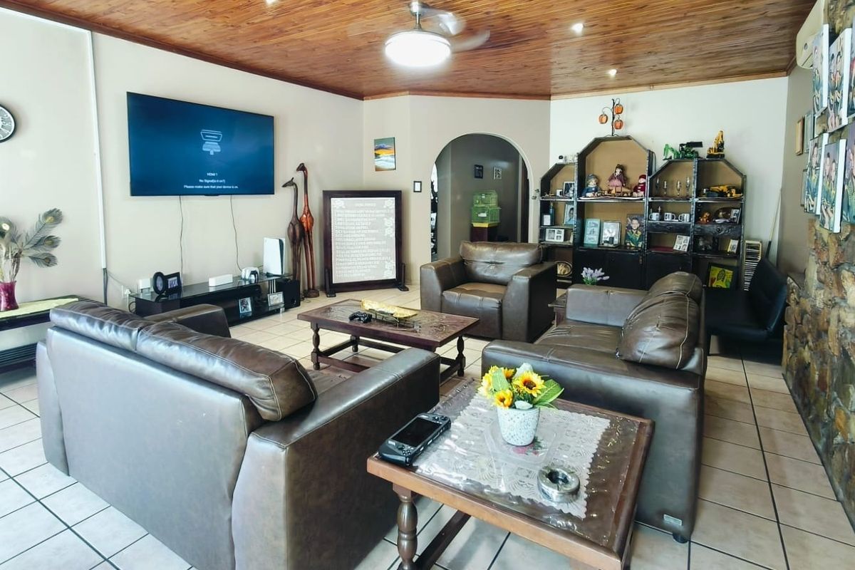 Spacious living room featuring a warm timber tongue and groove ceiling, ceramic tiled flooring, and a rustic stone feature wall.