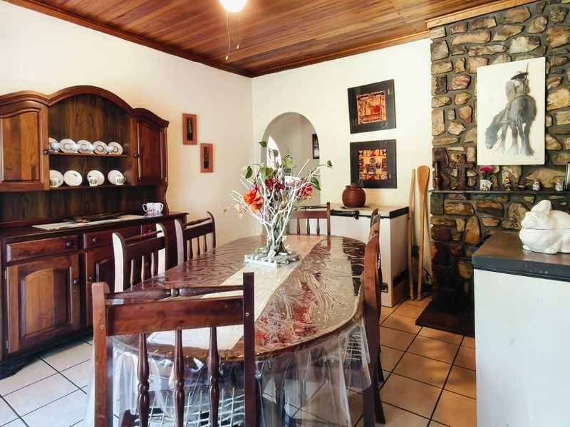 Dining room featuring a rustic stone fireplace, warm timber ceiling, and ceramic tiled flooring, creating a traditional and cozy atmosphere.