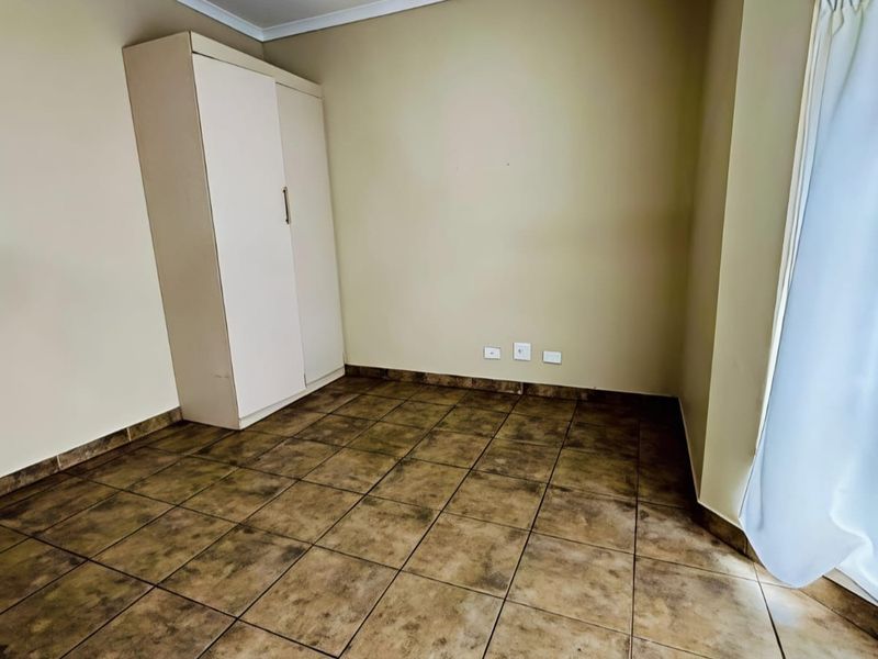 A vacant bedroom featuring tiled flooring and a built-in wardrobe, offering a neutral canvas ready for personalization.