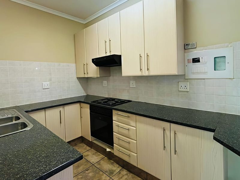 A functional kitchen featuring light-toned built-in cabinetry, dark laminate countertops, a built-in oven with gas hob, and a double bowl stainless steel sink.