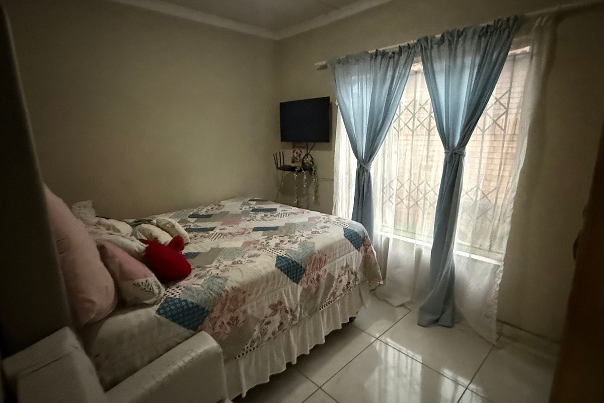 A functional bedroom featuring tiled flooring and a window fitted with a security gate.
