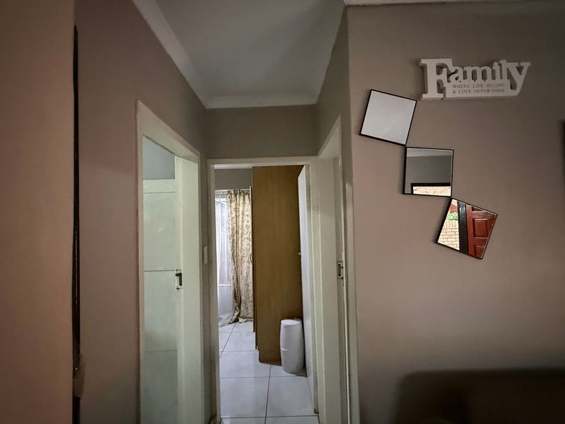 A functional hallway connecting multiple rooms, featuring neutral wall tones and tiled flooring throughout.