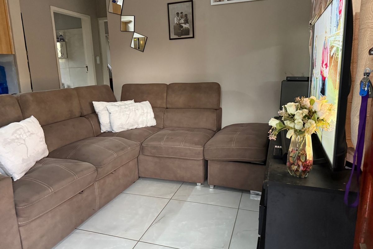 A comfortable living room featuring light-colored tiled flooring and neutral wall tones, providing a functional and well-maintained space for relaxation.