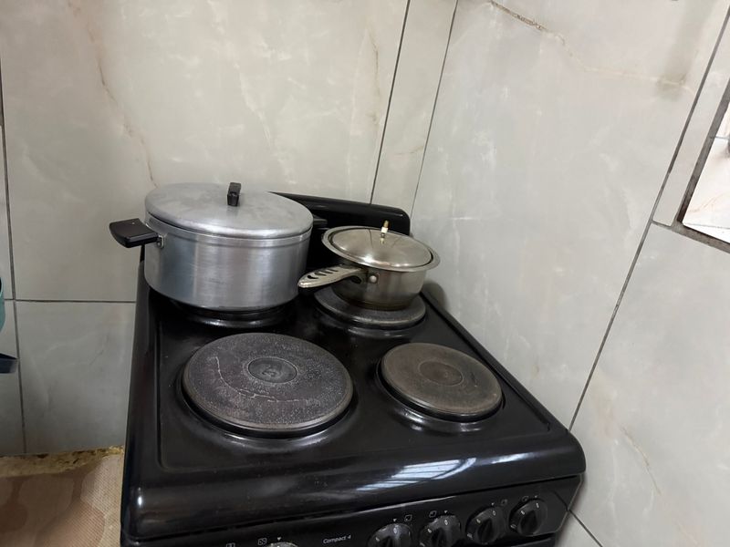A close-up view of a black electric stove with ceramic wall tiling in the background.
