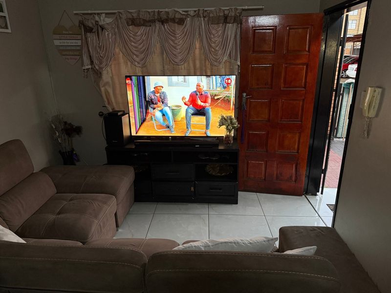 A living room area featuring tiled flooring and a solid wood panel door leading to the exterior.