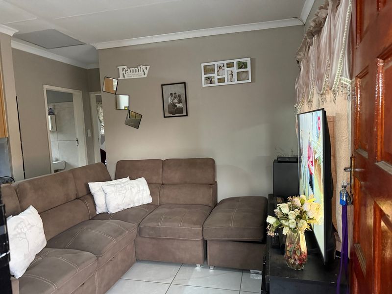 A comfortable living room featuring neutral wall tones, tiled flooring, and a coved ceiling, providing a functional and inviting space.