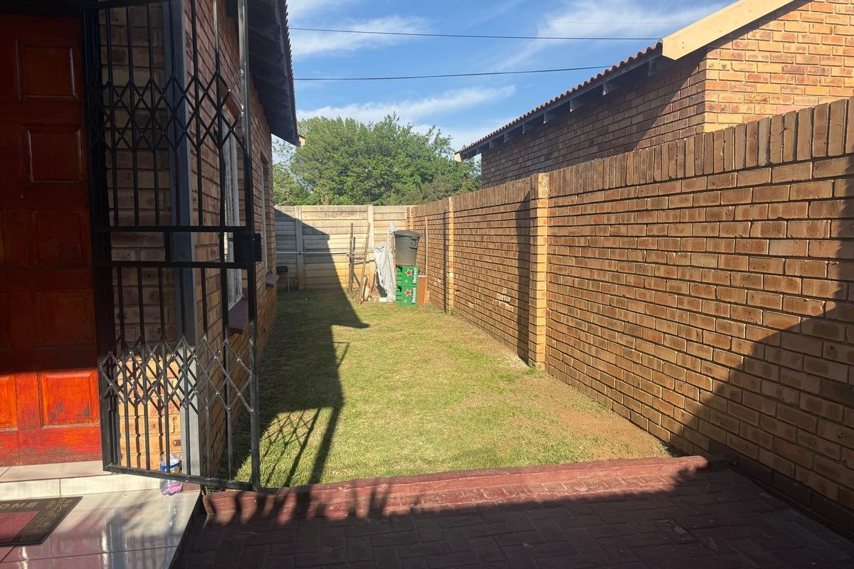 A private rear garden area featuring a paved patio, a small lawn, and secure brick boundary walls.