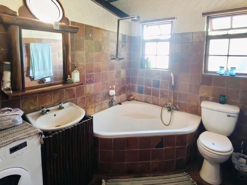 A dated bathroom featuring a corner bathtub, pedestal sink, toilet, and tiled walls. The space offers functional fixtures in need of modern updates.