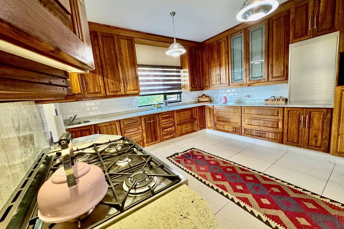 A well-maintained kitchen featuring warm wooden cabinetry, stone countertops, a gas hob, and a classic subway tile backsplash with ample storage space.