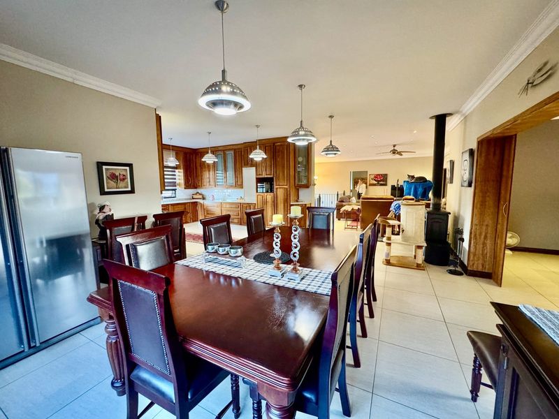 Spacious open-plan dining and kitchen area featuring warm wooden cabinetry, tiled floors, and a cozy freestanding fireplace.