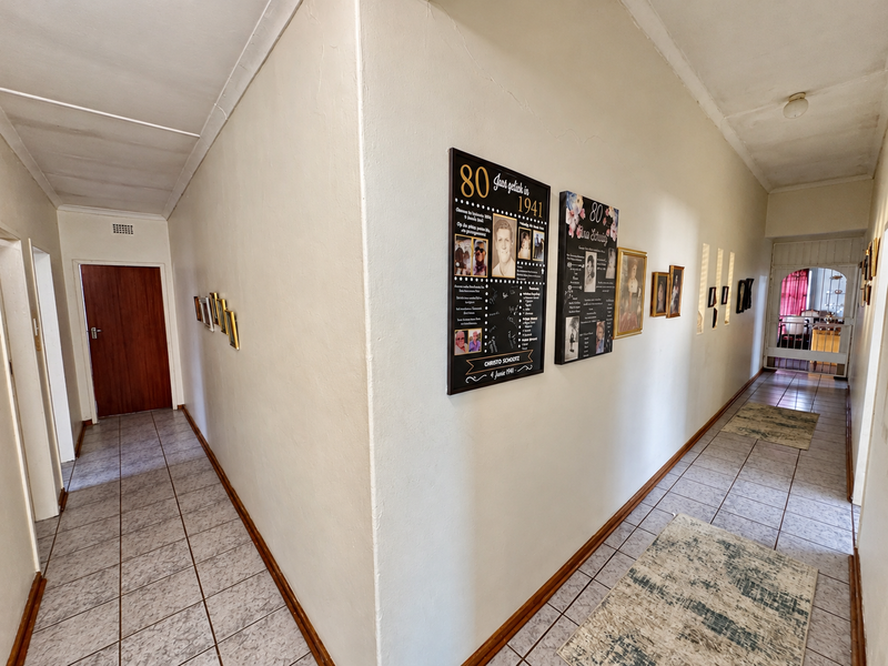 A spacious L-shaped hallway featuring tiled flooring, neutral walls, and access to multiple rooms, providing a clean and functional transition space.