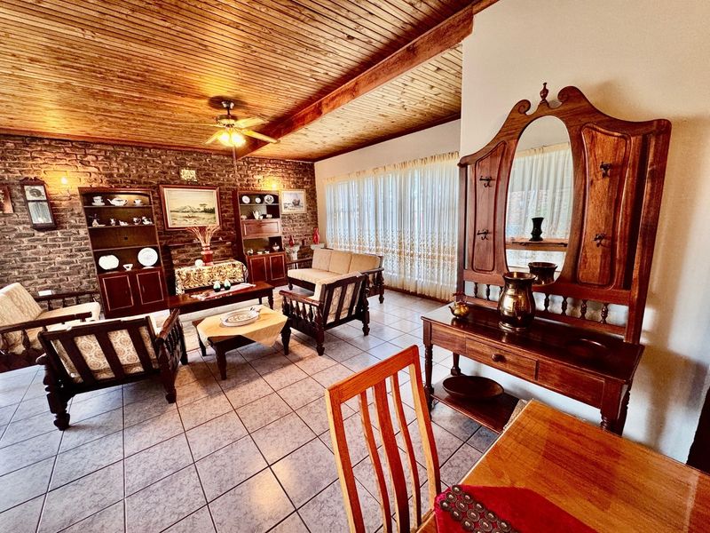 Spacious living room featuring a rustic exposed brick wall, warm timber tongue and groove ceiling, and neutral ceramic floor tiles.