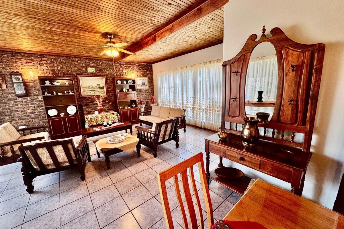 Spacious living room featuring a rustic exposed brick wall, warm timber tongue and groove ceiling, and neutral ceramic floor tiles.