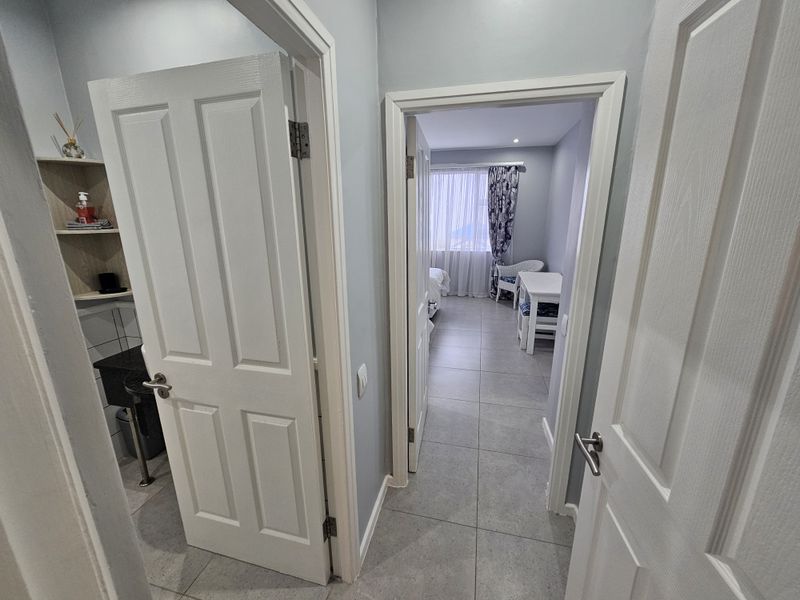 A clean, tiled hallway providing access to adjacent rooms, featuring neutral wall tones and classic panel doors.