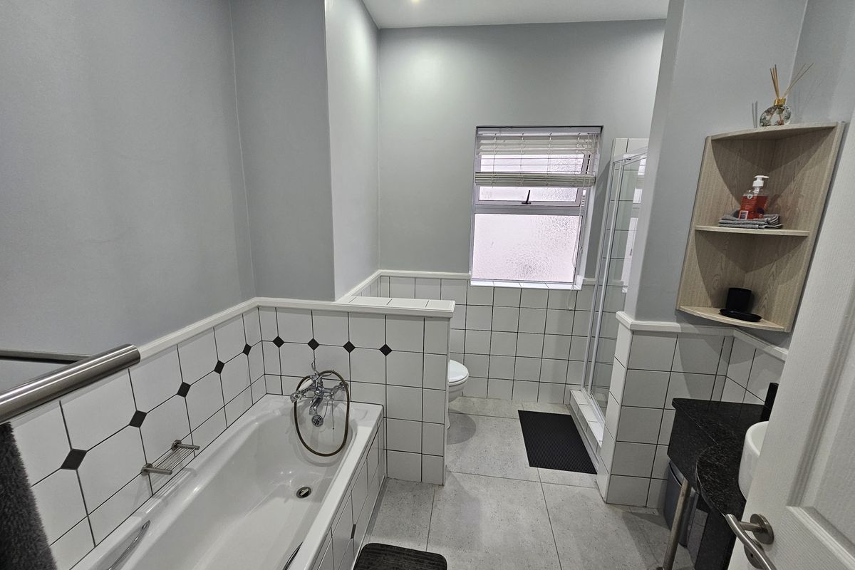 A well-maintained bathroom featuring a built-in bathtub, separate shower enclosure, and a vanity with a stone countertop.